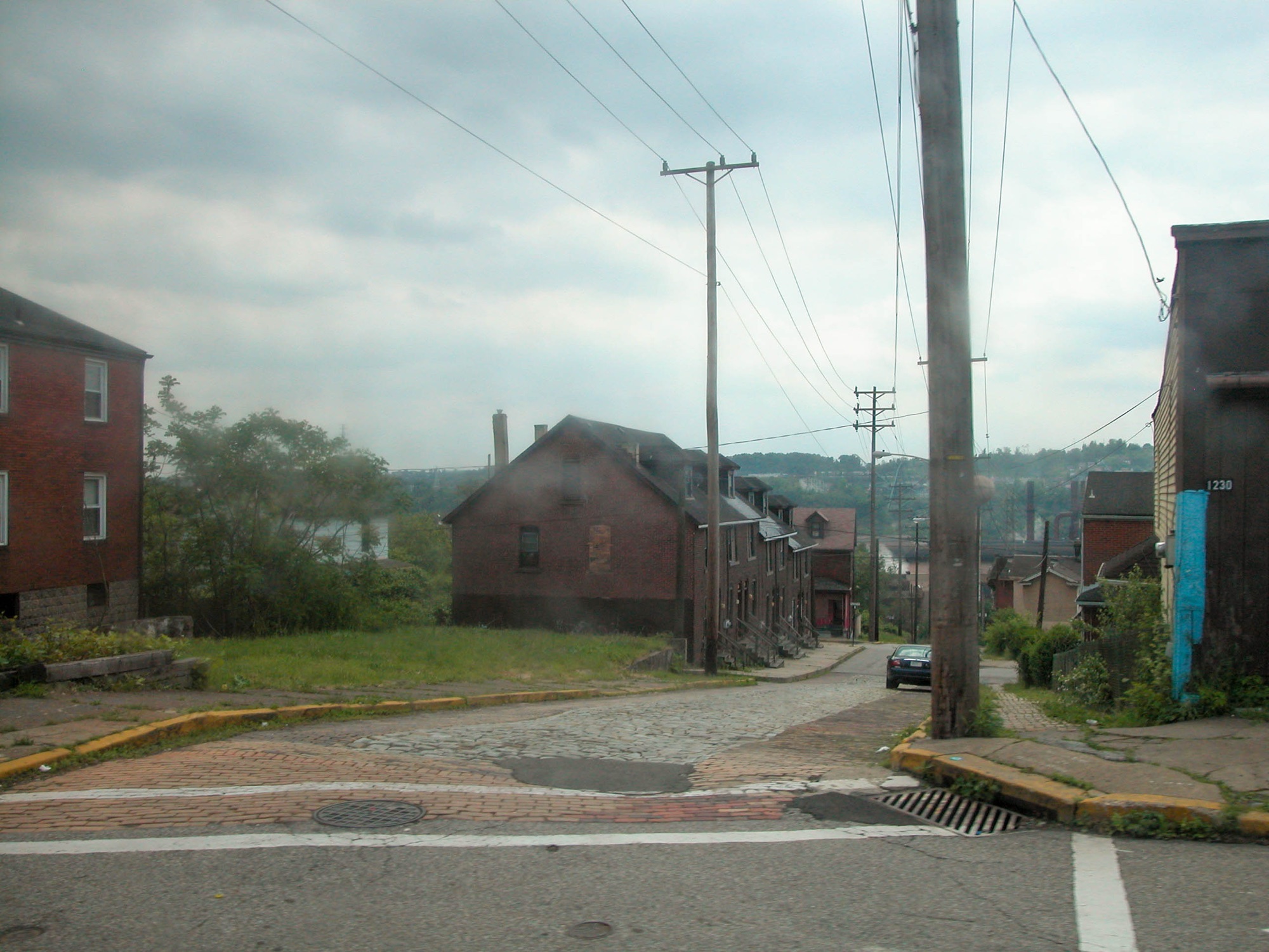 A Braddock hillside street of rowhouses with the steel mill in the haze, 2007.