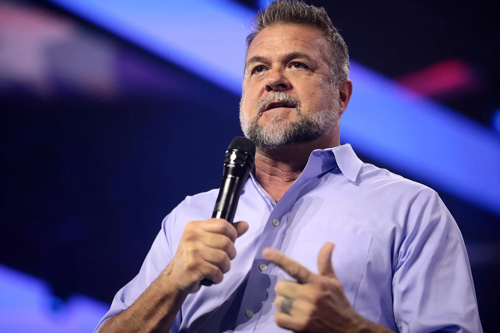 Victor Marx, in a light blue shirt, speaking into a microphone at a Turning Point USA convention in Phoenix.